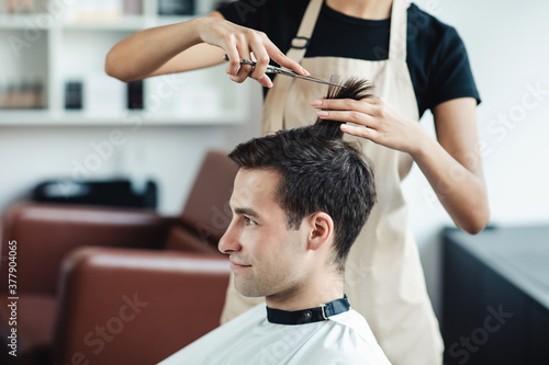 Young guy cutting hair at professional barber shop, free space