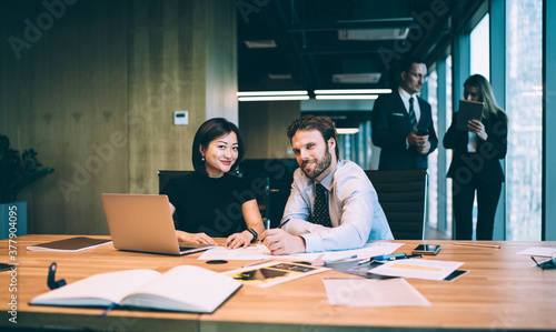 Cheerful multiethnic woman and man coworking in open space office