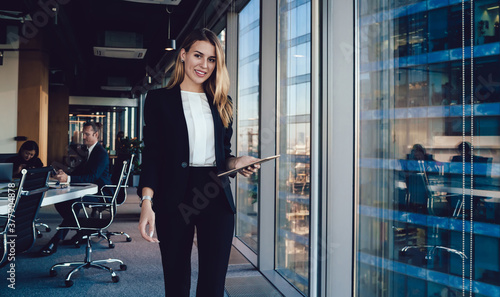 Delighted businesswoman using tablet in office photo