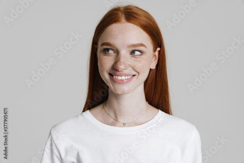 Image of happy ginger girl smiling and looking aside