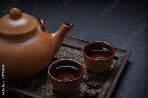 Cup of tea with teapot and dried tea leaves on a bamboo tray photo