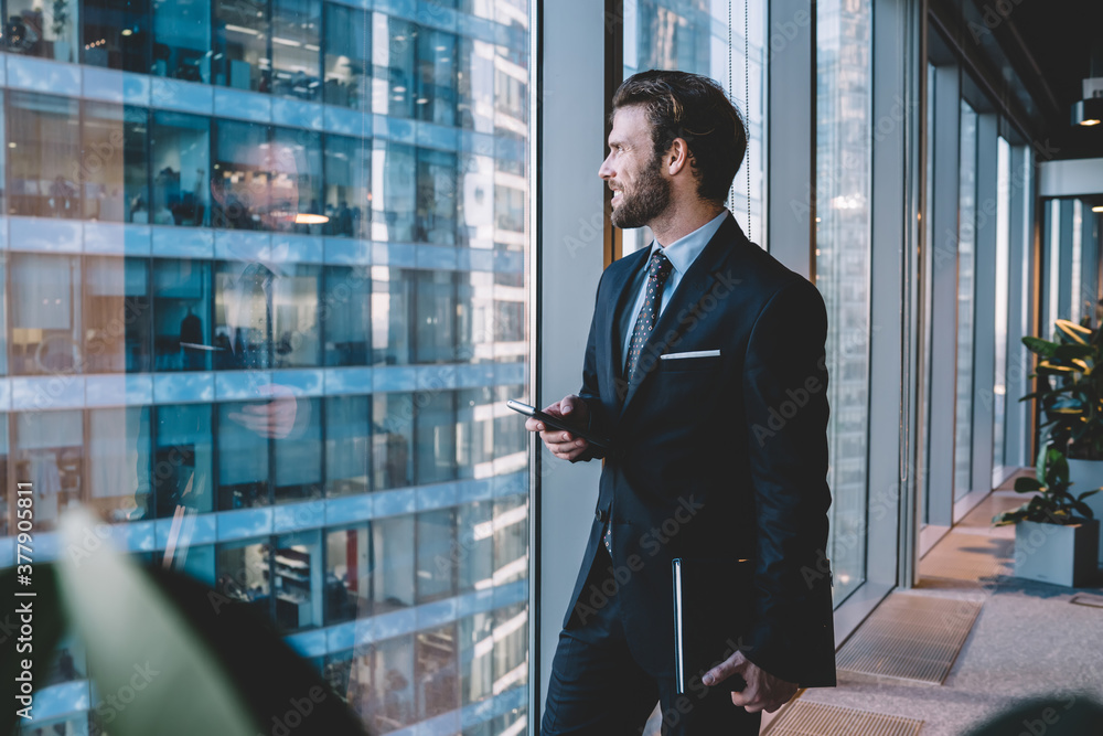 Fototapeta premium Content male executive manager surfing Internet on cellphone in office
