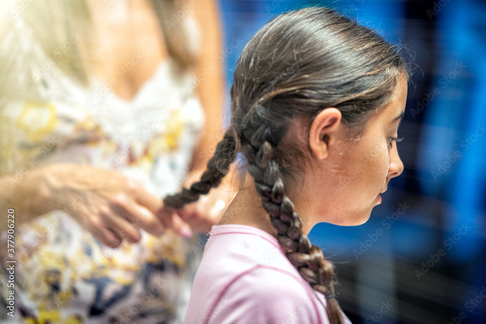 Naklejka premium Woman combing her daughter's hair at home before school