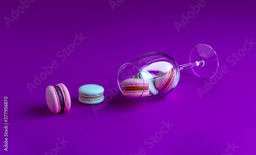 Assorted macarons field with cream in a glass on a purple background. 
