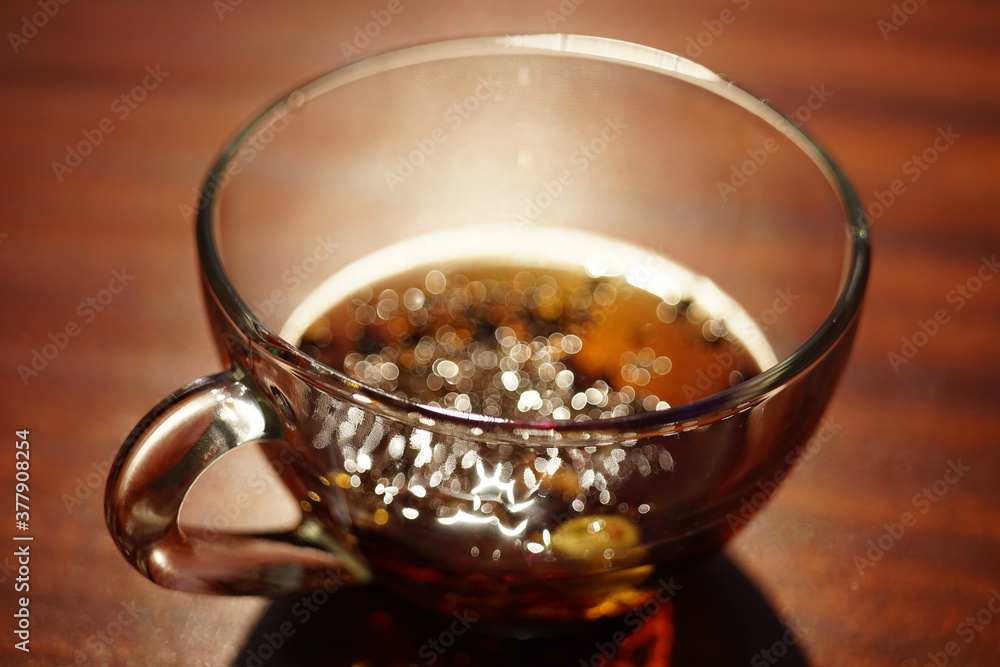 Glass cup with black tea on the brown wooden table. Closeup view Glass cup with black tea on the brown wooden table. Closeup view
