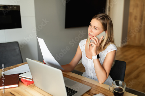 Woman with smartphone and laptop working at home office