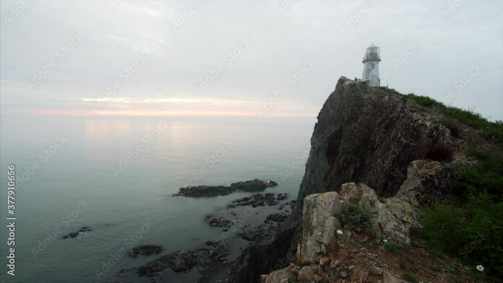 Timelapse of a high rocky cliff above the sea and the lighthouse on its top. Light morning fog. Far East of Russia Timelapse of a high rocky cliff above the sea and the lighthouse on its top. Light morning fog. Far East of Russia