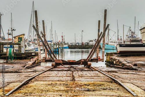 An industrial rail boat ramp or boat deployer on platform in Dragor Harbour. Rusty marine railway or slipway on tracks in a fishermen village harbor seems misused and abandoned - Dragor Havn, Denmark