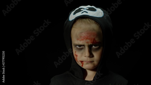 Halloween  angry girl with blood makeup on face. Kid dressed as scary skeleton  posing  making faces