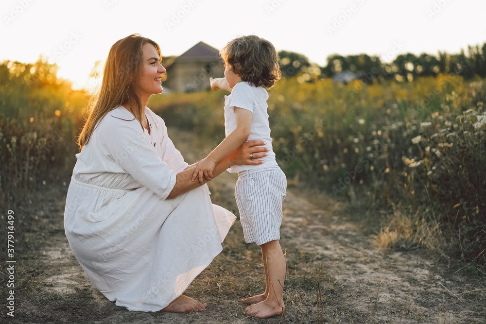 Woman playing with her child on the field during sunset. Woman playing with her child on the field during sunset.