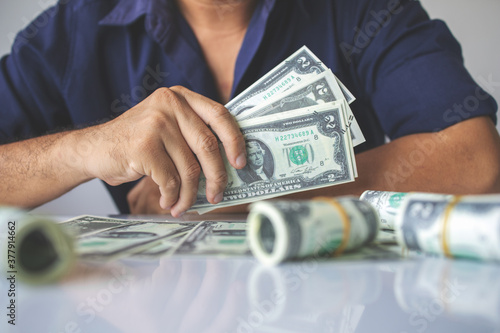 Foto closeup hands holding us dollar bills with soft-focus and over light in the back