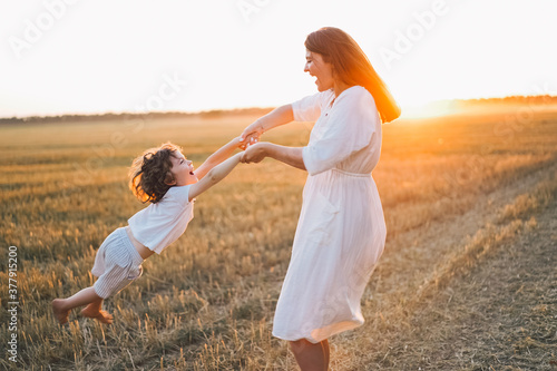 Woman playing with her child on the field during sunset.
