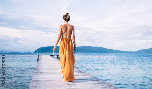 Tableau sur toile Back view of female tourist enjoying resort vacations in paradise nature environ