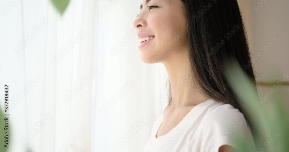 Pleased korean woman looking out through window Pleased korean woman looking out through window