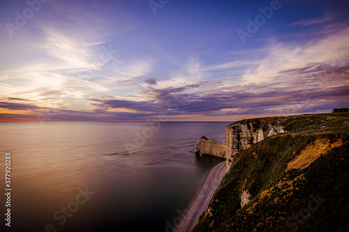 Beautiful sunset over calm sea and cliffs, Etetrat chalk cliffs, France