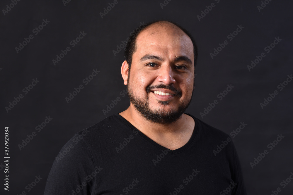 portrait of a latin american man on black  background,smiling