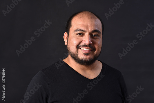 portrait of a latin american man on black background,smiling