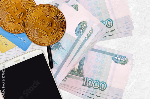 1000 russian rubles bills and golden bitcoins with smartphone and credit cards. Cryptocurrency investment concept. Crypto mining or trading photo