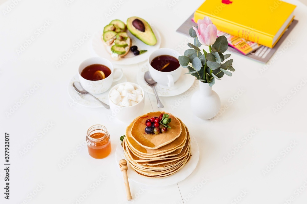 breakfast pancakes with honey and berries on a white table breakfast pancakes with honey and berries on a white table