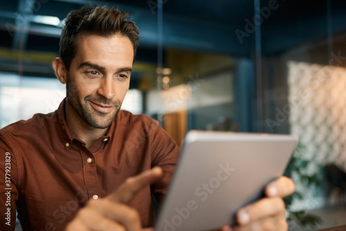 Smiling businessman using a tablet at his office desk