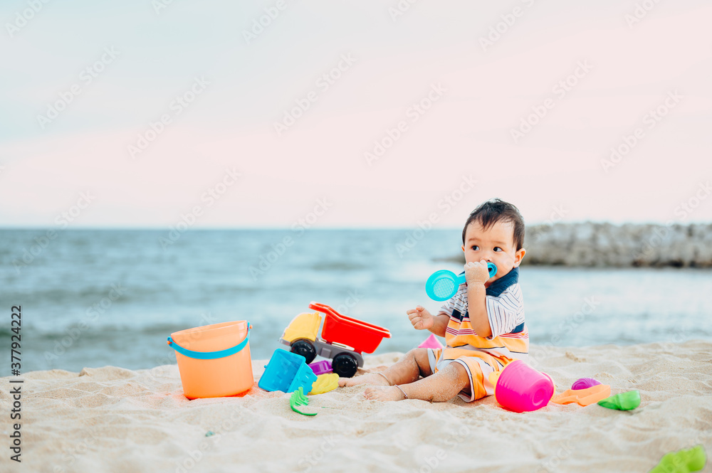 Baby boy playing with beach toys with his mother on tropical beach.Summer family vacation Baby boy playing with beach toys with his mother on tropical beach.Summer family vacation