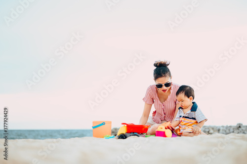 Baby boy playing with beach toys with his mother on tropical beach.Summer family vacation © grooveriderz