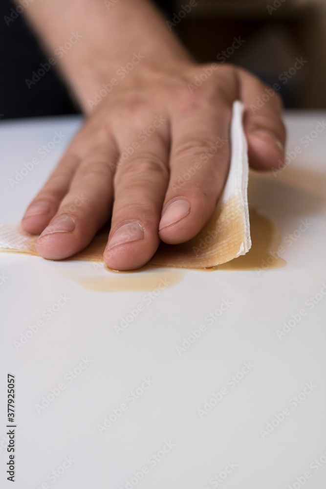 The guy wipes the table with a white disposable napkin