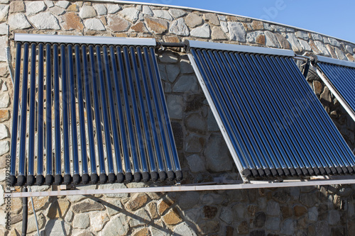 Solar water heating system installed on wall or roof of house. 3 panels of glass coaxial tubes with water to accumulate heat. Side view. Concept environmentally friendly and economical home heating