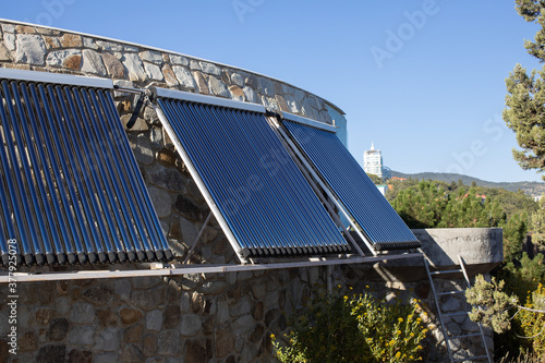 Solar water heating system installed on wall or roof of house. 3 panels of glass coaxial tubes with water to accumulate heat. Side view. Concept environmentally friendly and economical home heating