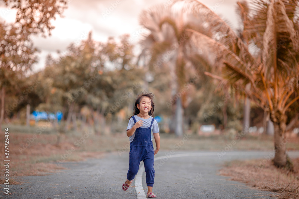 Blurred abstract background of Asian girls, cute in a bright dress, playing on the street or in a park, when parents watch closely.