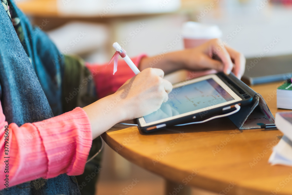 Fototapeta premium Close up hand of Asian woman in pink sweater use tablet for e-learning
