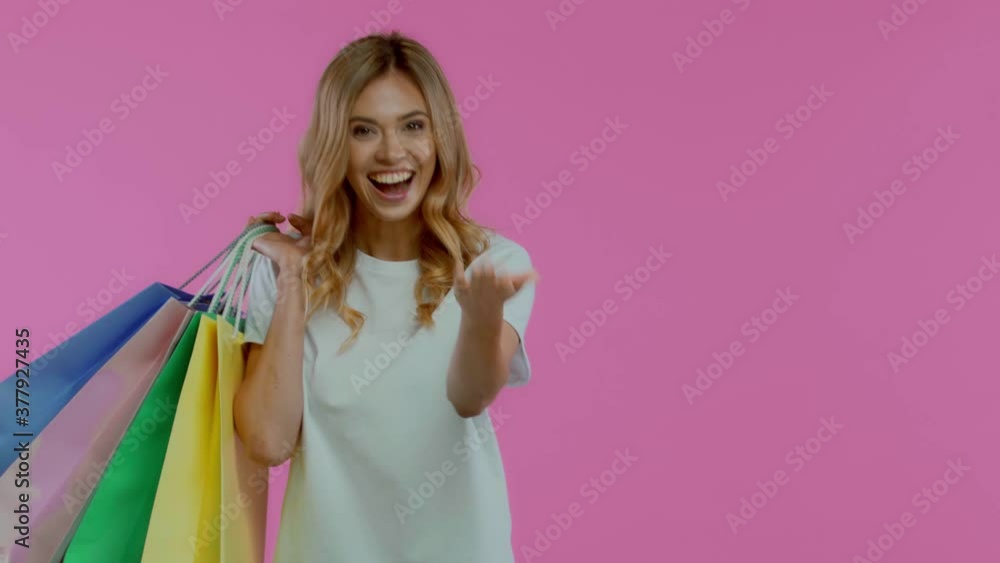 Blonde woman with shopping bags gesturing isolated on purple Blonde woman with shopping bags gesturing isolated on purple