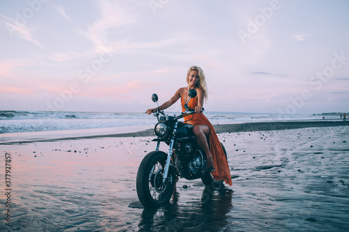 Young woman on motorbike smiling on beach