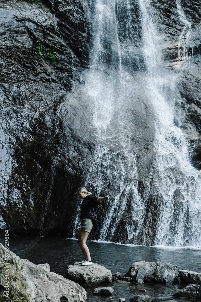 Obraz premium young woman on the background of a mountain waterfall with a ponytail 
