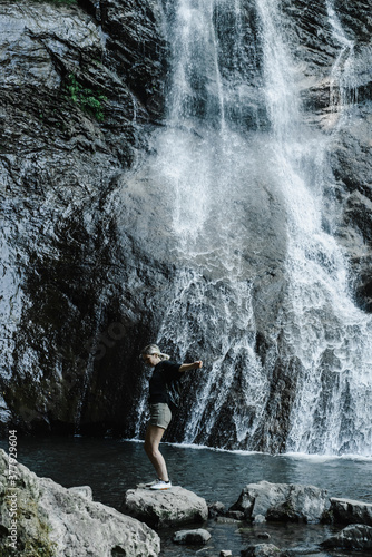 young woman on the background of a mountain waterfall with a ponytail 