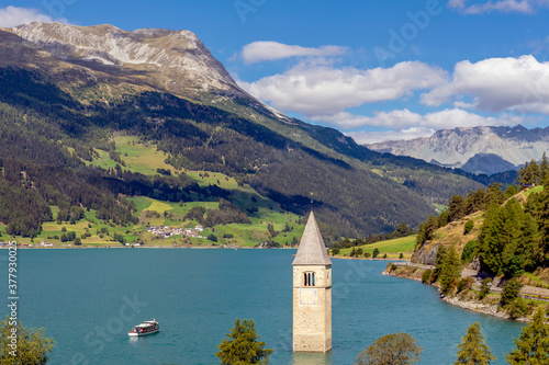 Top view of a cruise on Lake Resia near the old submerged bell tower of Curon Venosta, South Tyrol, Italy