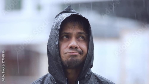 close up young man wearing a raincoat in the rain slow motion