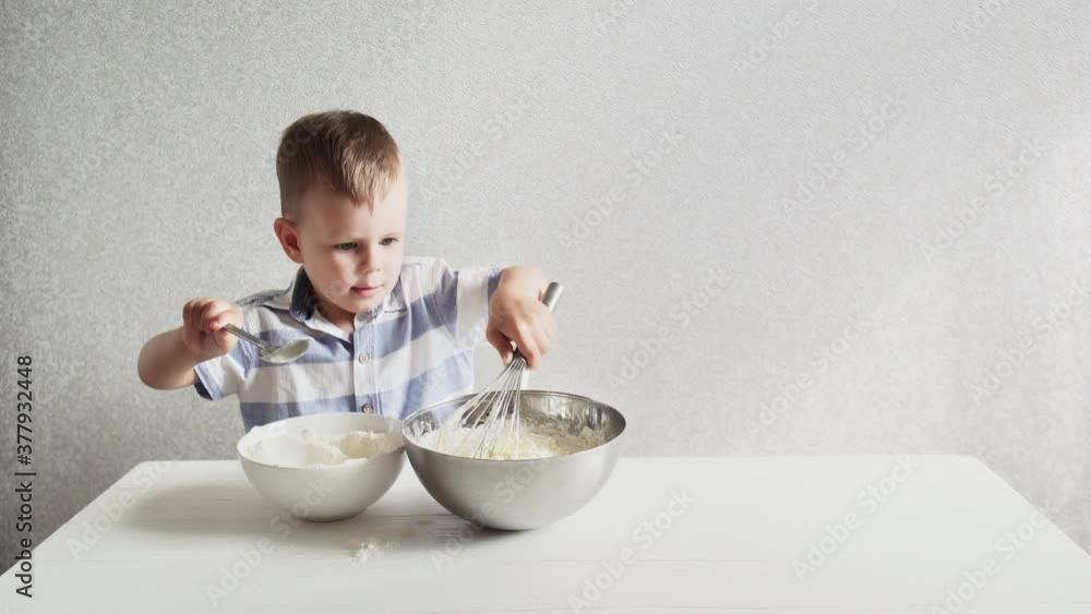 Young preschool boy cooking dough for cake by himself standing alone on white kitchen at home. Young preschool boy cooking dough for cake by himself standing alone on white kitchen at home.