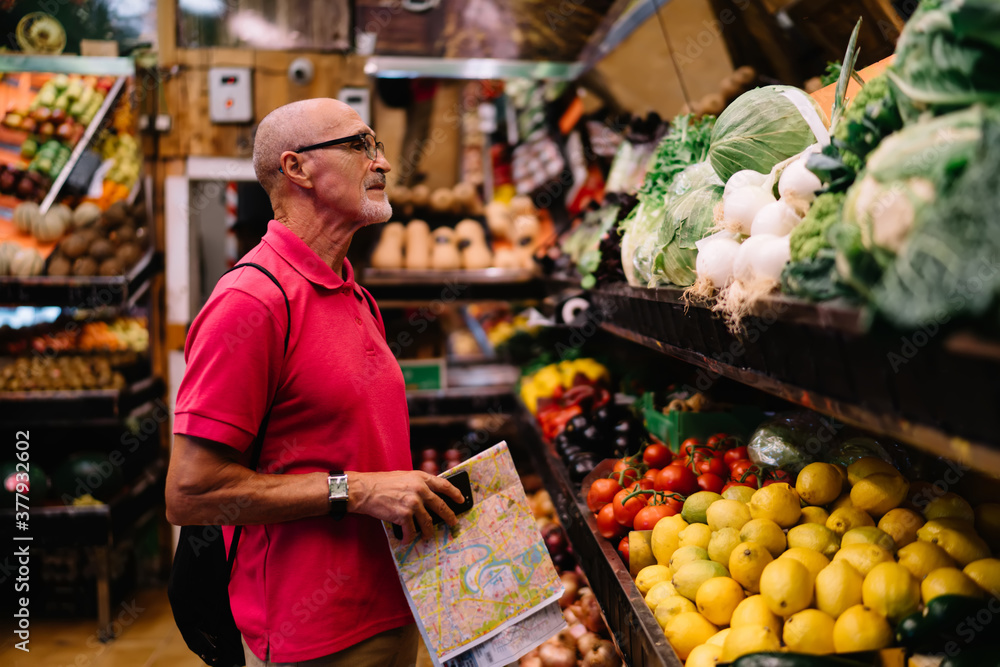 Elderly man standing at counter with vegetables