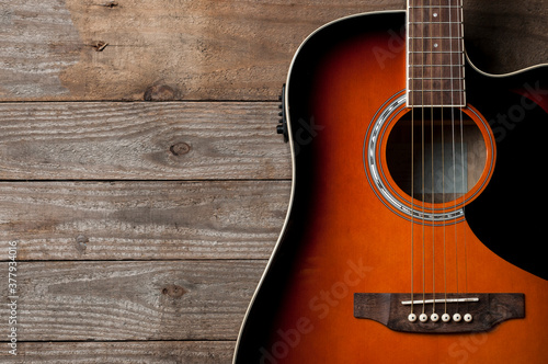 A black and orange acoustic guitar on wooden floor