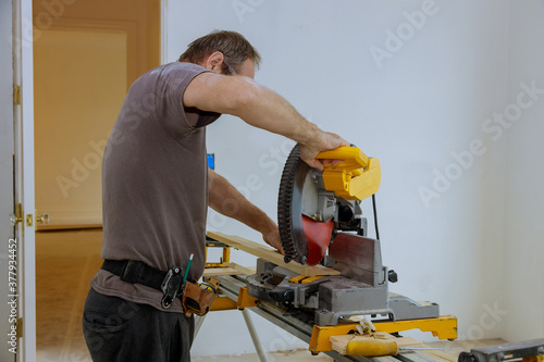 Man cut the wooden molding with circular saw