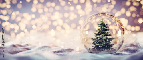 Christmas tree in glass ball on snow. Glitter lights photo