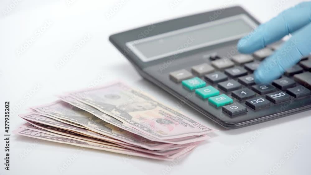 Person in latex glove using calculator near dollars on white background Person in latex glove using calculator near dollars on white background