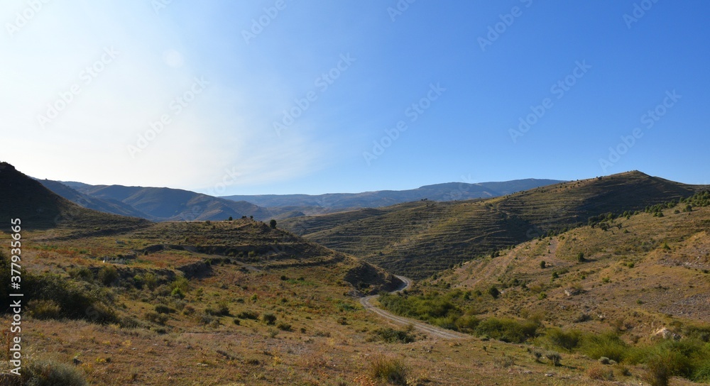 Dirt track in the Las Bargas ravine. Blue sky and sun appearing on the left.