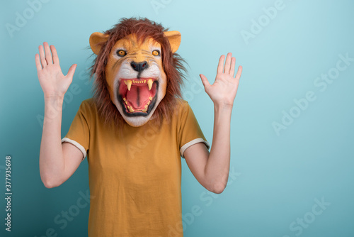 Young woman in lion mask holding hands up in desense or stop gesture. photo