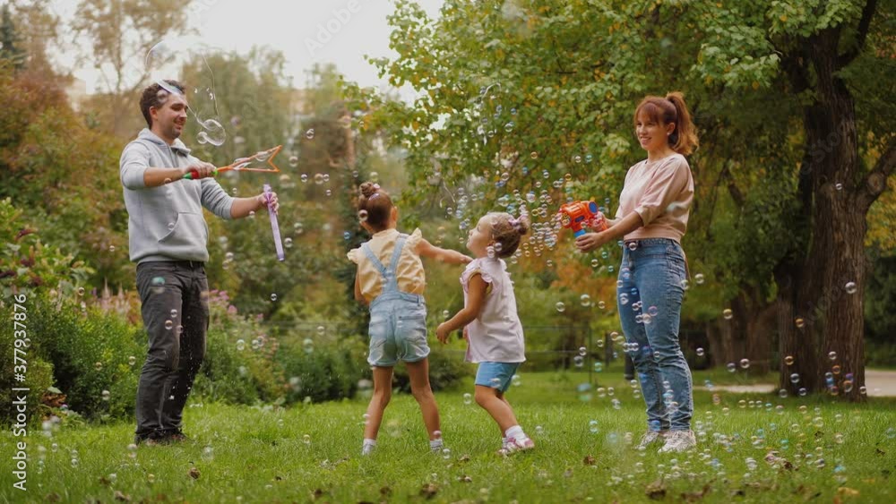 Parents and kids having fun together with soap bubbles in summer park Parents and kids having fun together with soap bubbles in summer park