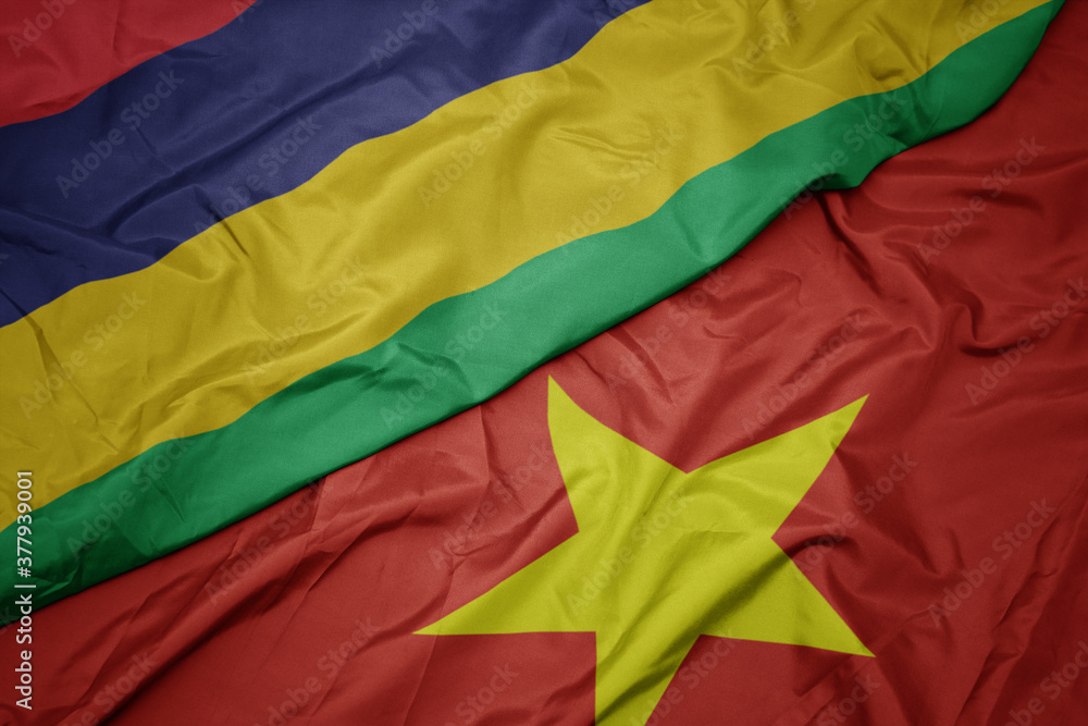 waving colorful flag of vietnam and national flag of mauritius.