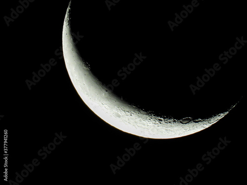 a waning moon stands as crescent moon in the black night sky