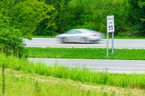 Speeding Car Streaks By Speed Limit Sign