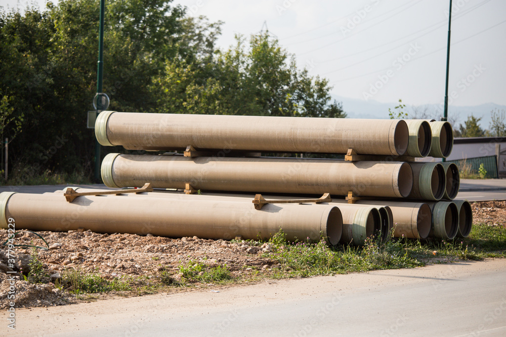 Large sewer pipes, slid along the road, ready for installation, reconstruction of roads and sewer networks Large sewer pipes, slid along the road, ready for installation, reconstruction of roads and sewer networks